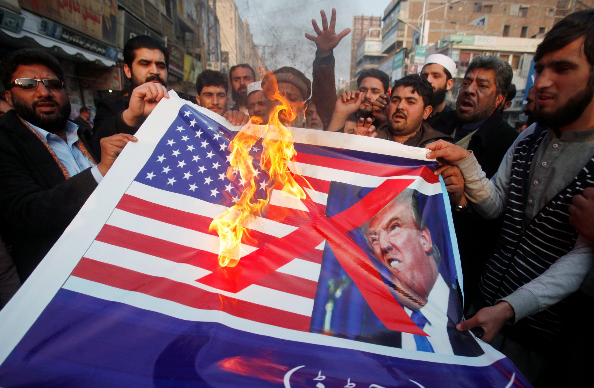 US announces the suspension of financial aid to Pakistan: People burn a sign depicting a U.S. flag and a picture of U.S. President Trump as they take part in an anti-U.S. rally in Peshawar | REUTERS