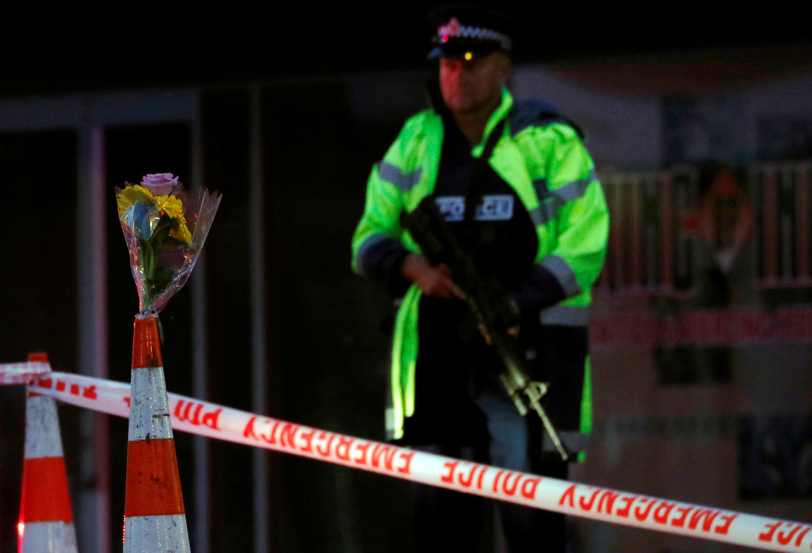 An armed police officer stands guard next to flowers offered by a resident outside Linwood mosque after Friday's gunmen attacks, in Christchurch, New Zealand March 16, 2019. REUTERS/Edgar Su - RC1FF1E1B160