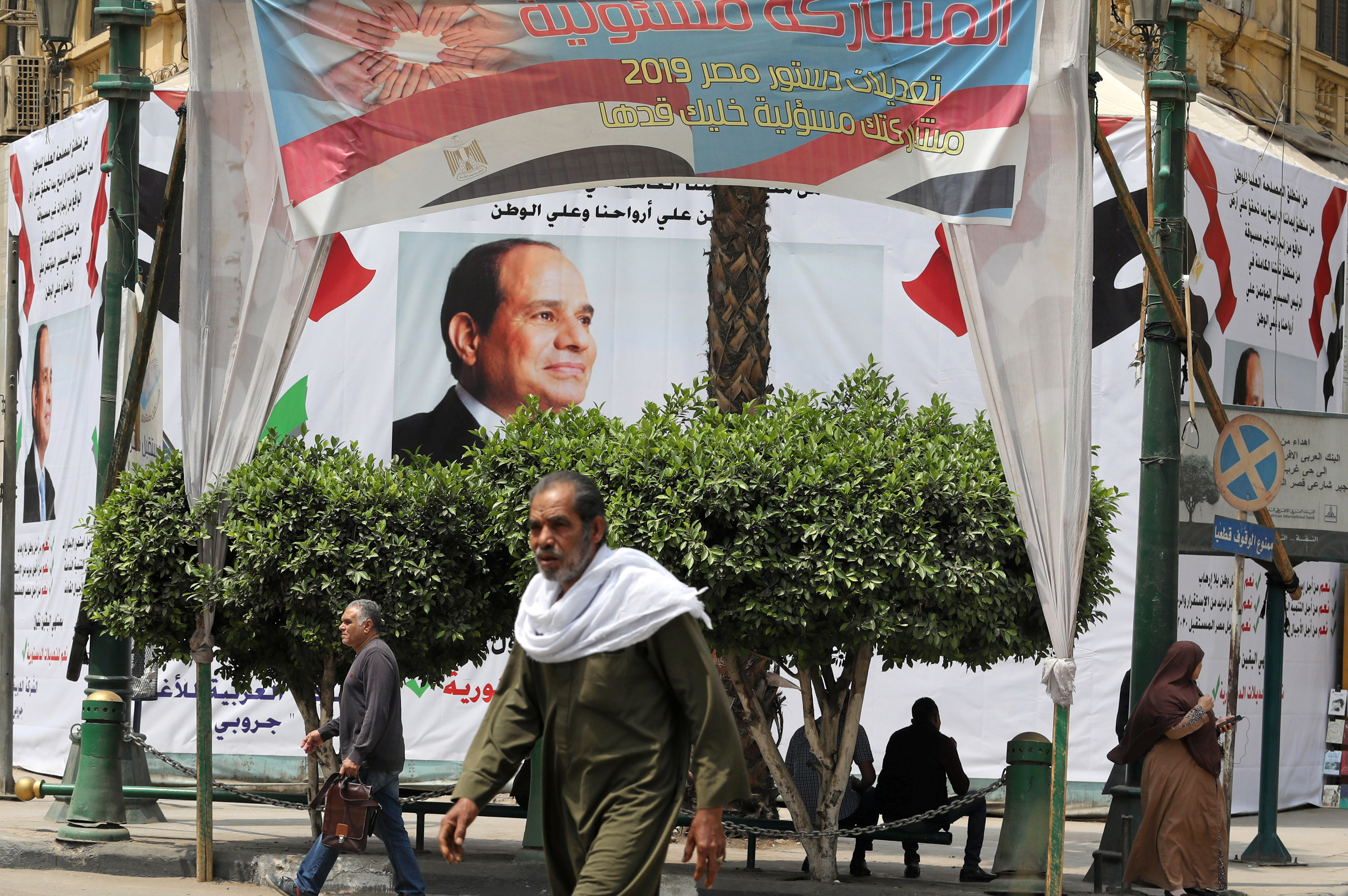 Pedestrians walk in front of a banner of the Egyptian President Abdel Fattah al-Sisi before the upcoming referendum on constitutional amendments in Cairo, Egypt April 16, 2019. REUTERS/Mohamed Abd El Ghany - RC125CB524E0