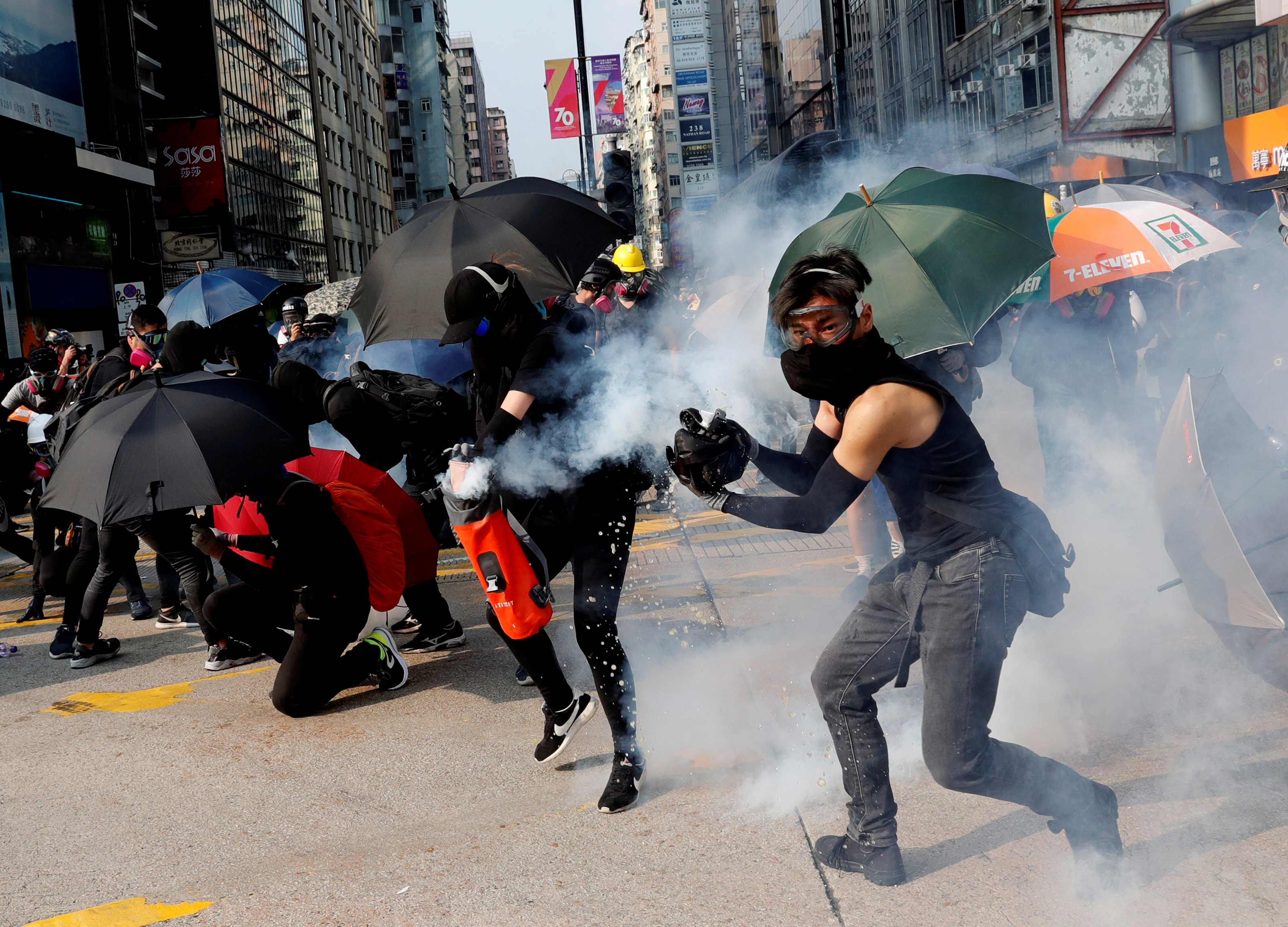 An anti-government demonstrator puts out a tear gas canister with a bag holding water during a protest in front of Tsim Sha Tsui Police Station in Hong Kong, China, October 20, 2019. REUTERS/Kim Kyung-Hoon - RC179FE05390